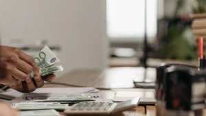 Profesional contando euros junto a una calculadora para analizar el periodo medio de cobro