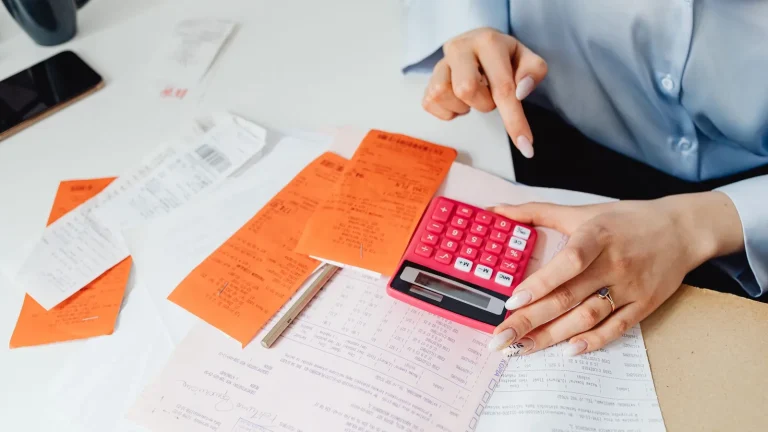 Profesional revisando recibos y gastos con una calculadora
