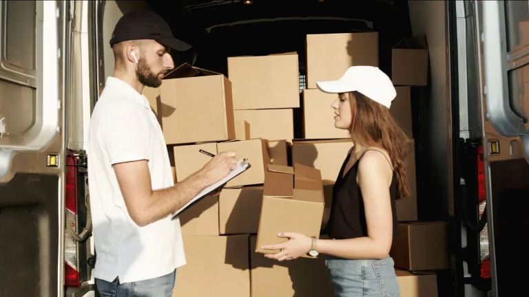 Personal de reparto organizando paquetes en un vehículo de transporte